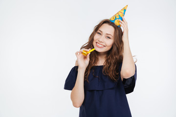 Canvas Print - Cheerful young woman in birthday hat with party whistle