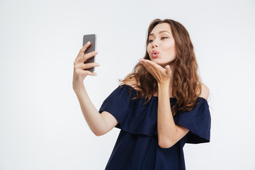 Wall Mural - Happy woman sending a kiss and taking selfie with smatphone