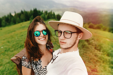 Wall Mural - stylish  hipster couple traveling and smiling on top of mountain