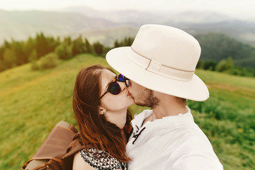 Wall Mural - stylish  hipster couple traveling and kissing on top of mountain