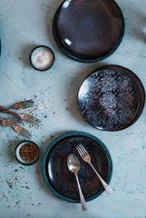 Empty dinning black decorative three bowls over turquoise stone table with cutlery complements