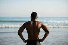 Back View Of Black Fit Sportsman Looking The Sea For Motivation Before Swimming. Male Swimmer Ready For Outdoor Training Into The Ocean.