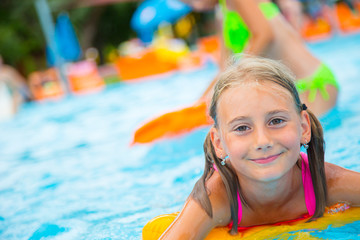 Happy girl child playing in the pool on a sunny day. Cute little girl enjoying holiday vacation.