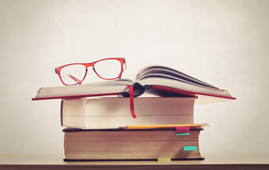 glasses on books with pencil