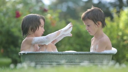 Poster - Two children, boy brothers, having a bath outdoors, making soap bubbles, summertime