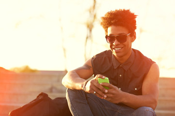smiling urban hipster young man using smart phone