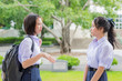 © 9'63 Creation - Cute Asian Thai high schoolgirls student couple in school uniform talking and discussing with her friend face expression in green background