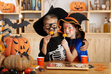 Hugging Brother And Sister In Halloween Costumes Eating Treats