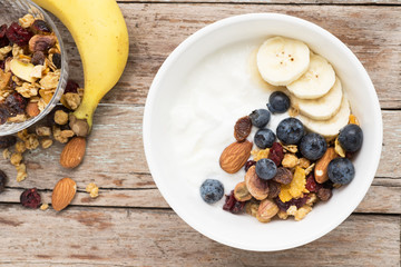 Wall Mural - brunch : homemade yogurt with granola and banana in bowl on wooden table background.
