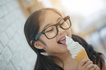 Wall Mural - Happy Asian girl enjoy eating soft ice-cream