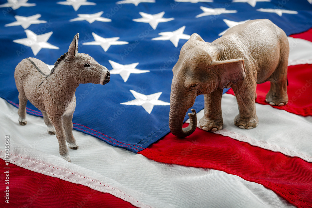 Democrats vs republicans are facing off in a ideological duel on the american flag. In American politics US parties are represented by either the democrat donkey or republican elephant - obrazy, fototapety, plakaty 