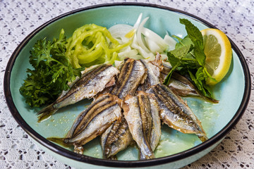 Poster - Cooked sardines with green salad in old-fashion plate on table