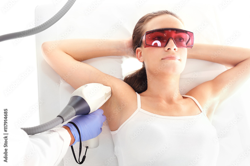 Klinika urody, depilacja laserowa. Kobieta na zabiegu depilacji laserowej - obrazy, fototapety, plakaty 