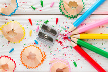 Colored Pencils And Pencil Sharpener On A White Wooden Background