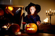© MNStudio - Adorable little girl wearing Halloween costume having fun with carved pumpkin