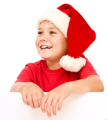 Little girl in santa hat is holding blank board