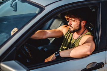 Hipster man driving a car on a sunny day