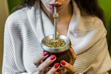 Young Woman Drinking Traditional Argentinian Yerba Mate Tea From A Calabash Gourd With Bombilla Stick. Selective Focus.