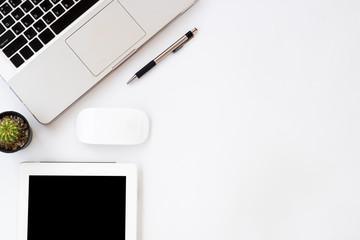 White office desk table with pen, laptop, mouse and empty screen tablet. Top view with copy space