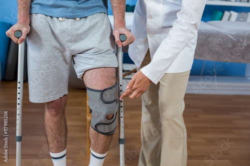 Fotografía Physiotherapist helping patient to walk with crutches