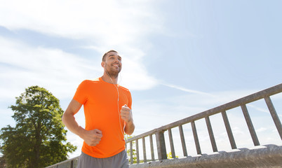 Canvas Print - happy man with earphones running outdoors