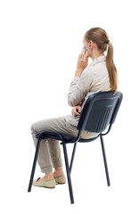 back view of young beautiful  woman sitting on chair.  girl  watching. Rear view people collection.  backside view of person.  Isolated over white background. Girl with long hair in a white jacket is