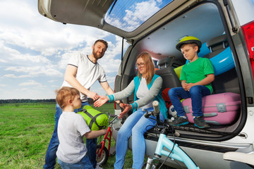 Kid boy helping his parents to load their car boot