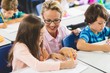 © WavebreakmediaMicro - Teacher helping girl with their homework in classroom