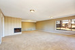 Empty beige room with fireplace and carpet floor.