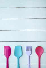 Colorful kitchen utensils arranged on a blue wooden table top background forming a page border