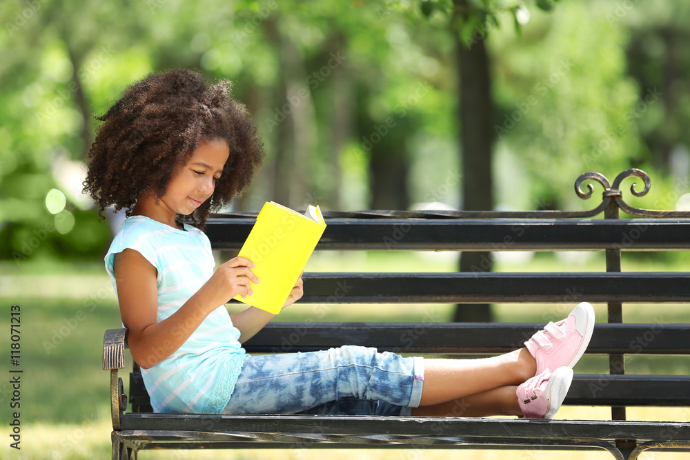 Cute girl reading book on bench