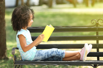 Wall Mural - Cute girl reading book on bench