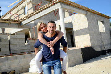 Wall Mural - cheerful young happy couple in love in front of contruction site of their new house