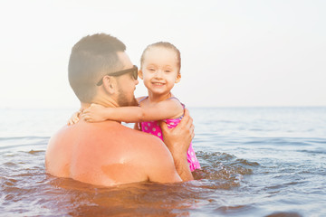 Wall Mural - father hugging daughter on the beach. parent has fun with her baby