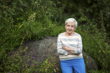 Wall Mural - An elderly woman stands in a green forest.