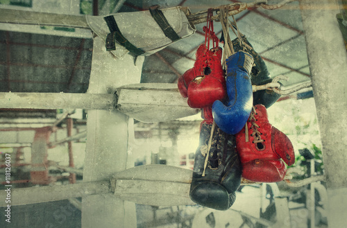 Fototapeta Para starych bokserskich rękawic Muay Thai wisi na ringu w obozie slumsów. Dodany efekt dodania do stworzenia atmosfery