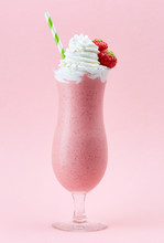 Glass of strawberry milkshake with whipped cream and fresh straw