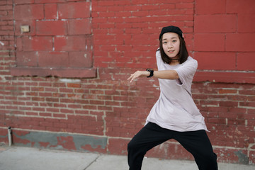 Wall Mural - Young Asian woman in city dancing hip hop