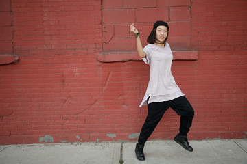 Wall Mural - Young Asian woman dancing hip hop in city