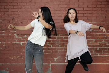 Wall Mural - Young Asian woman dancing hip hop in city