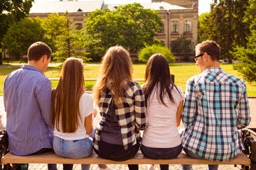 Canvas Print - back view photo of five diverse students sitting on bench and st