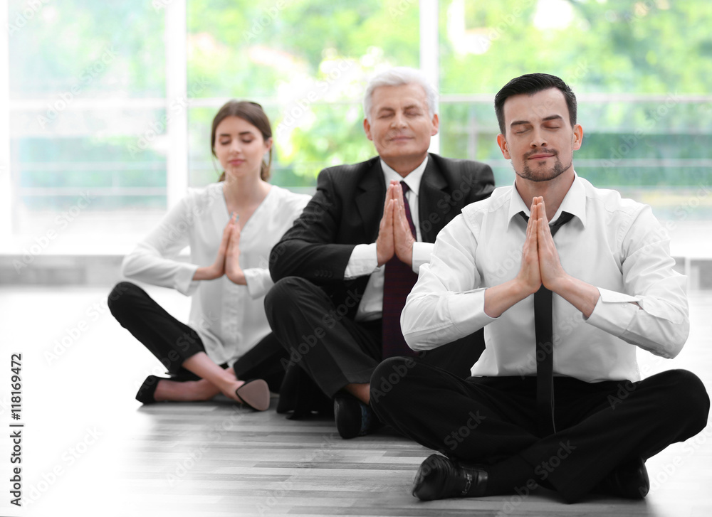 Business people relaxing in meditation pose in office