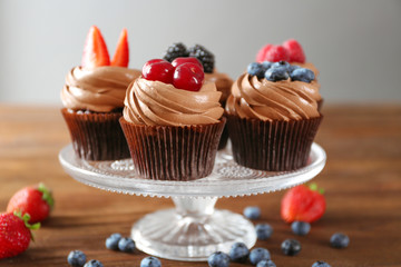 Tasty chocolate cupcakes with fresh berries on stand