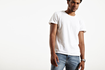 Attractive serious African American model with stubble on his face wearing distressed light blue jeans, plain white short-sleeved cotton t-shirt and retro digital watch with stainless steeel bracelet