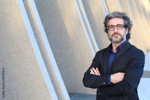 Cuadros en Lienzo Mature elegant professional with his arms proudly folded standing outside the of