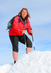 Overweight hiker woman on the top of snowy peak. Active people enjoying outdoor sports in mountain landscape. Healthy lifestyle and slimming concept.