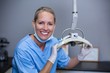 © WavebreakMediaMicro - Smiling dental assistant adjusting light in clinic