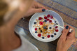 © Image Source - Over shoulder view of woman eating cereal and berry breakfast