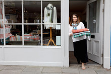 Shop Owner In Doorway Holding Fabric