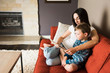 © Connect Images - Mother teaching son to read book on sofa